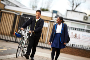 Two teenagers walking with a bike